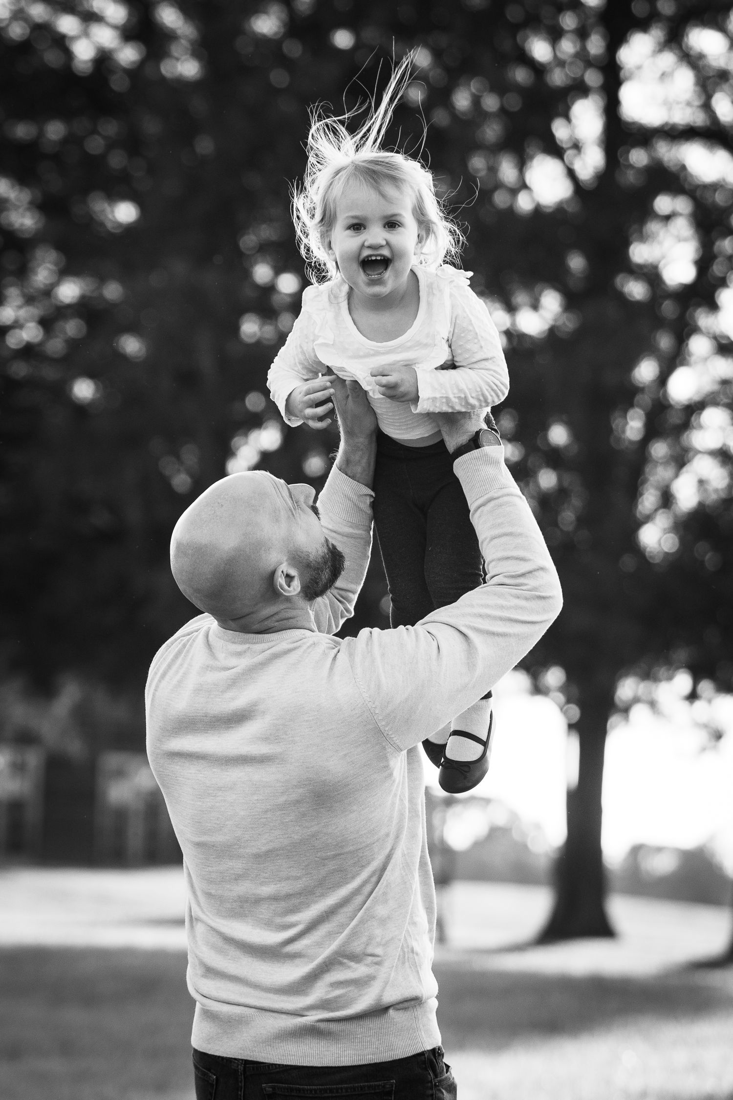 Black and white candid moment of playful interaction in a park setting.
