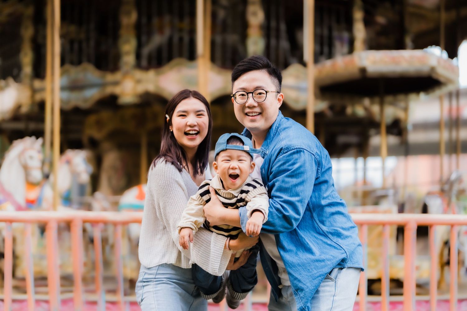 A happy family moment at an amusement park with a carousel in the background.