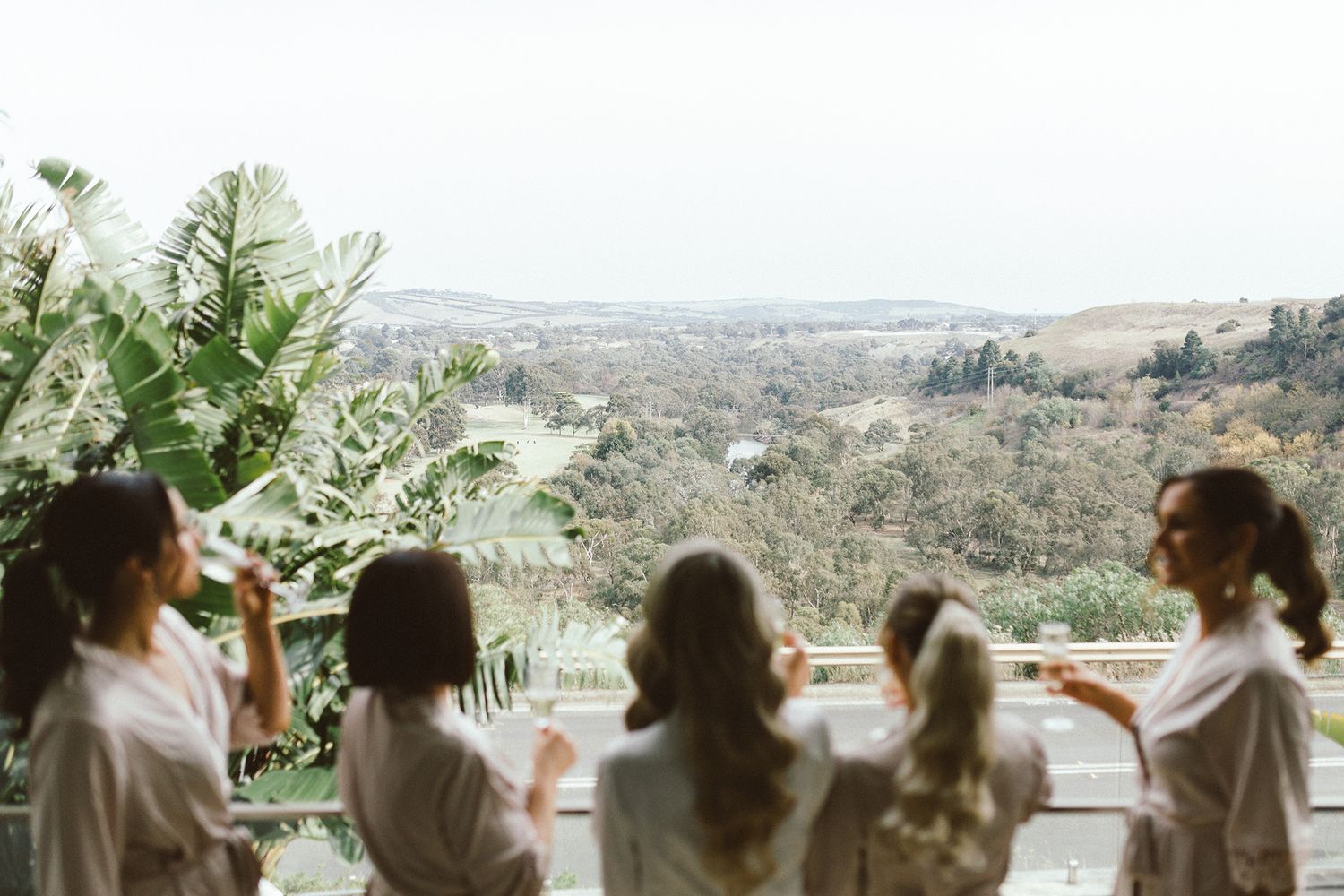 People in robes enjoying drinks while overlooking scenic mountain view.