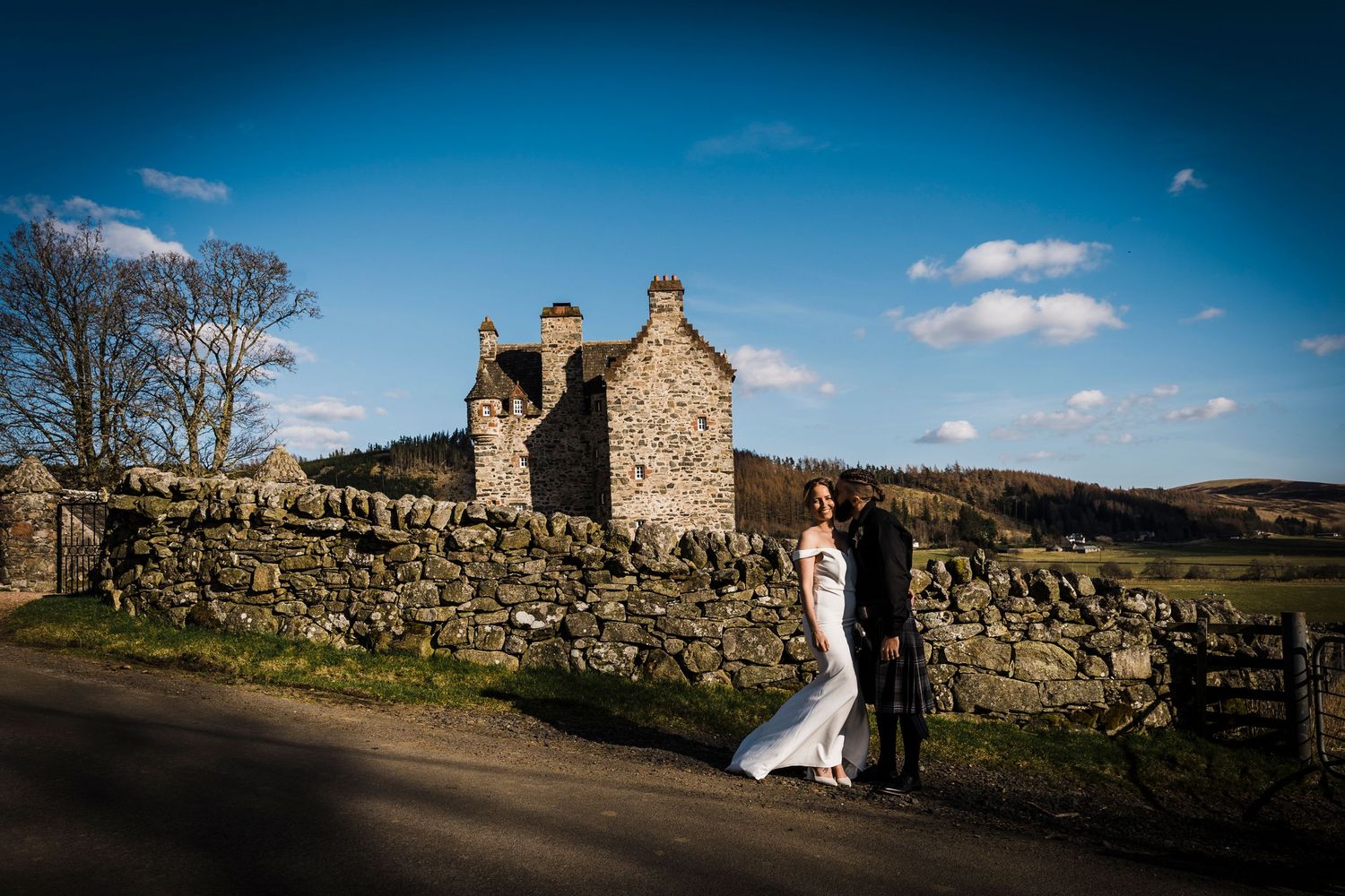 Bride and groom hugging with Scottish castle venue in background