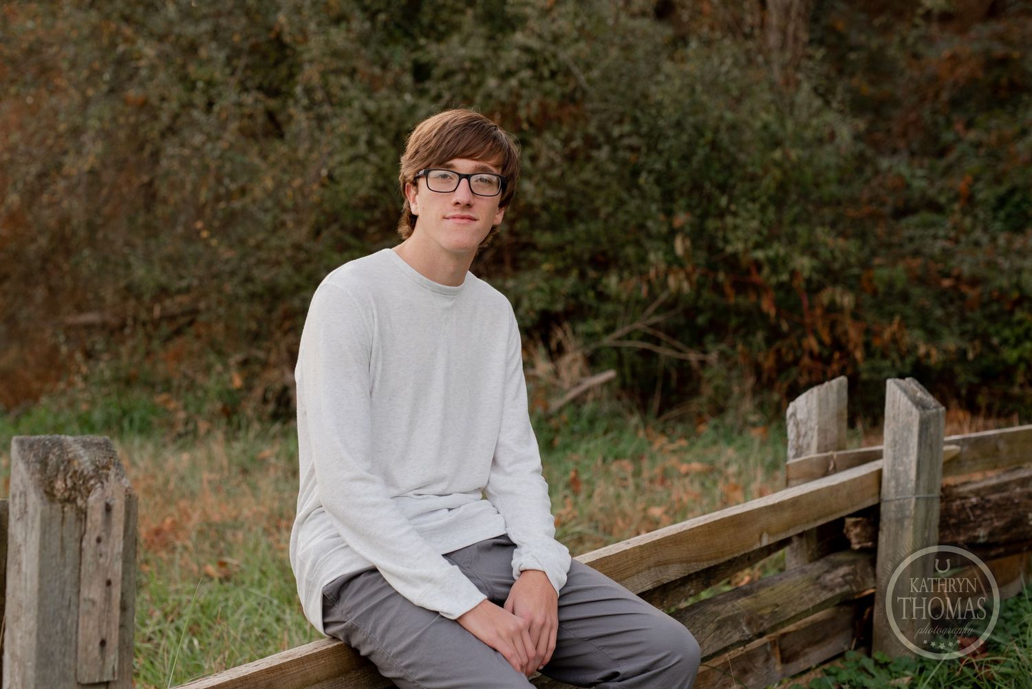 Casual portrait on wooden fence in rural autumn setting.