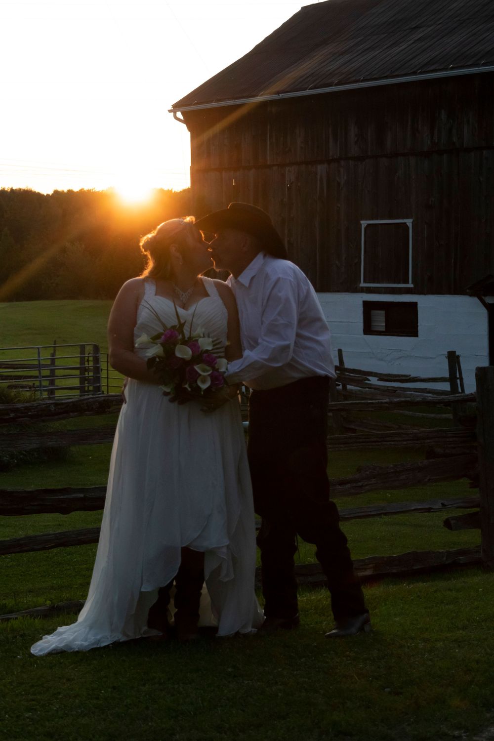 bride and groom kissing with sun setting