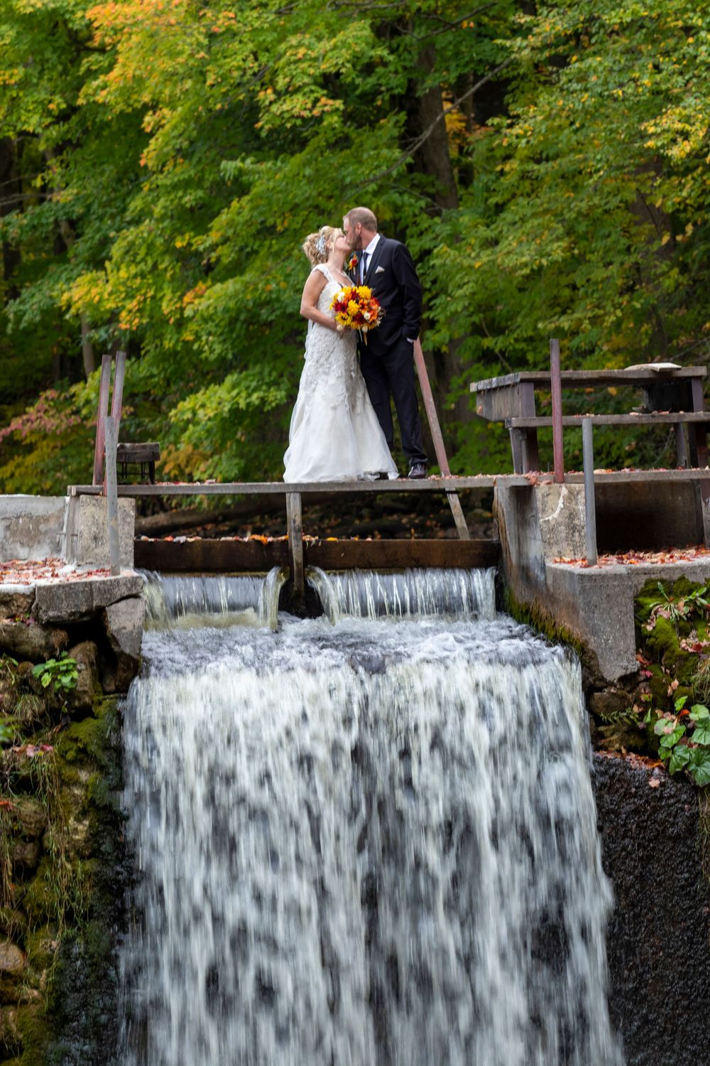 bride and groom standing on top of a waterfall