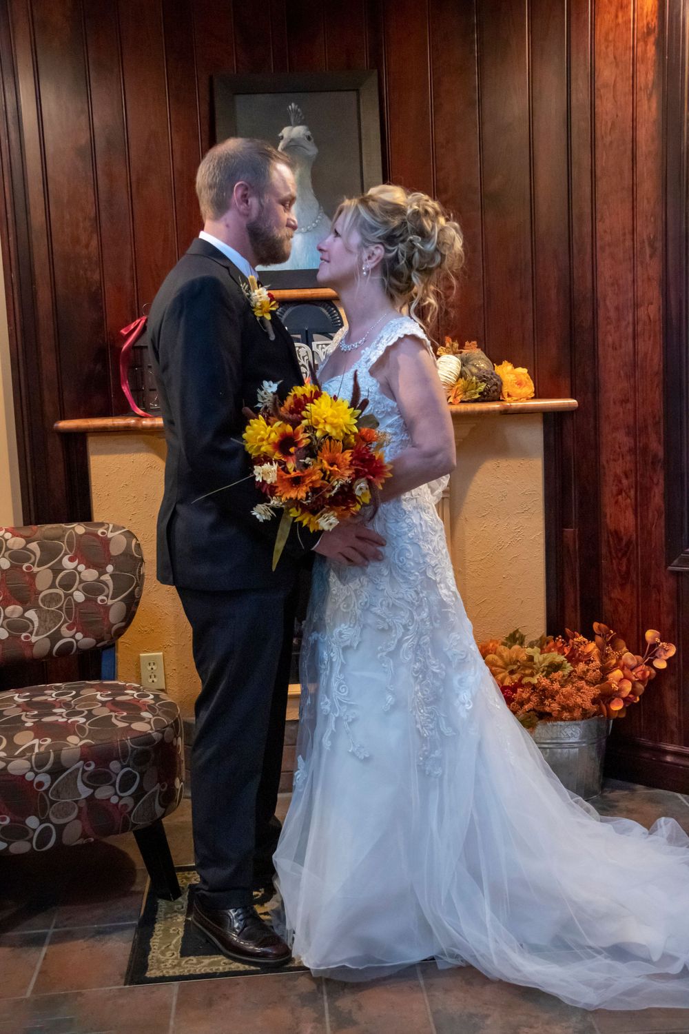 Bride and groom intimately lookin at each other in front of a fireplace