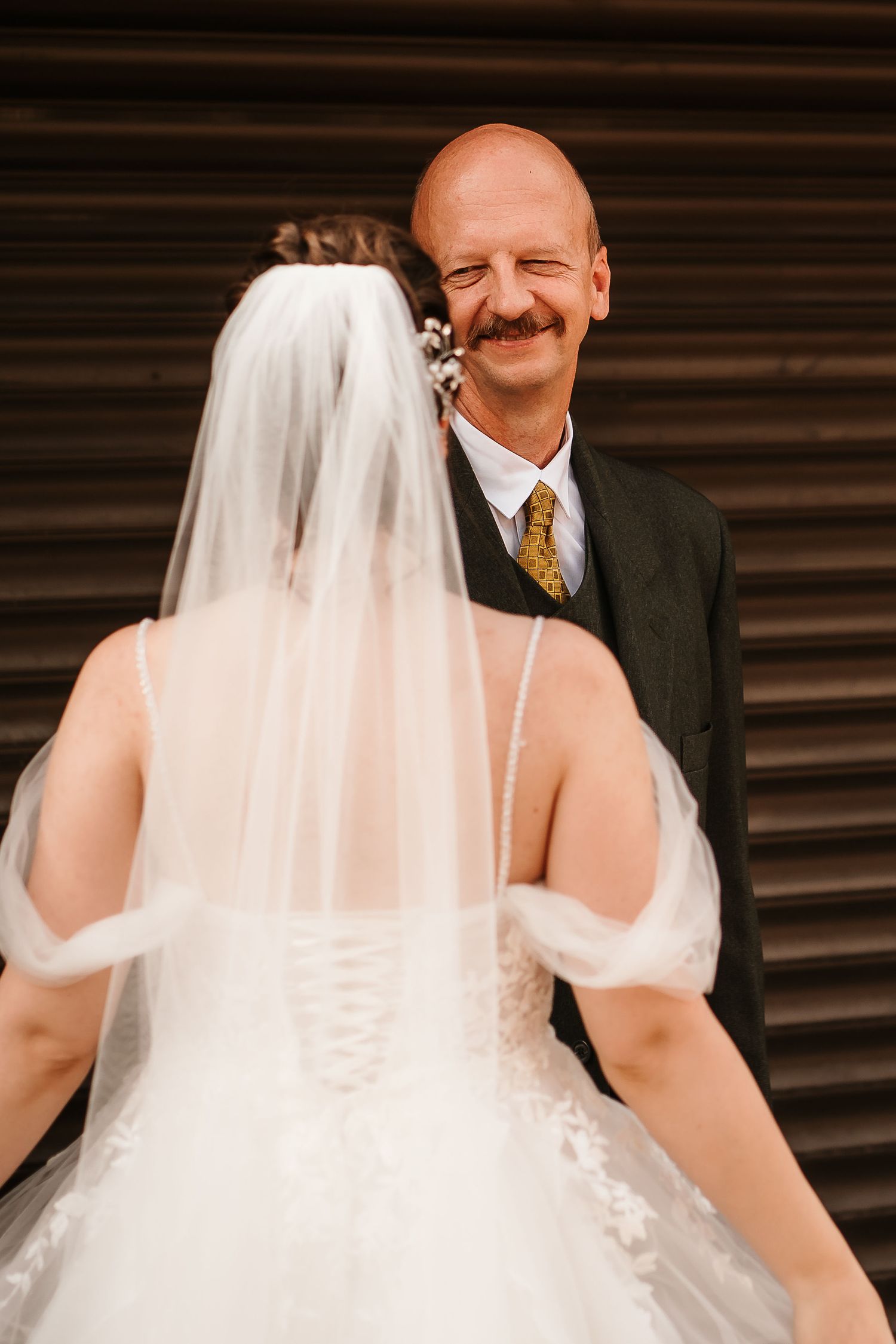 A tender moment between a bride and groom against a textured wall background.