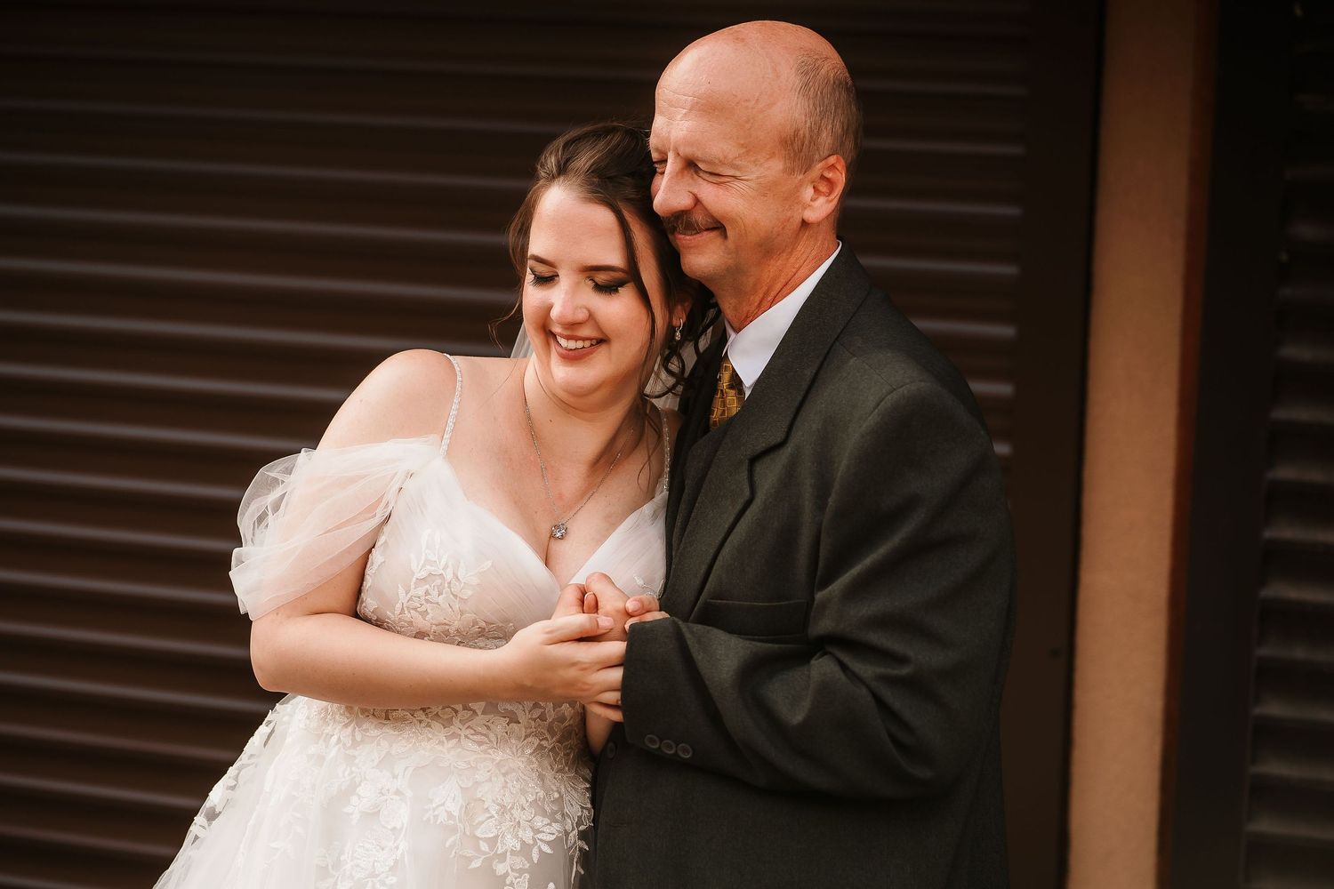 An intimate wedding portrait featuring laughter and embraces against a dark background.