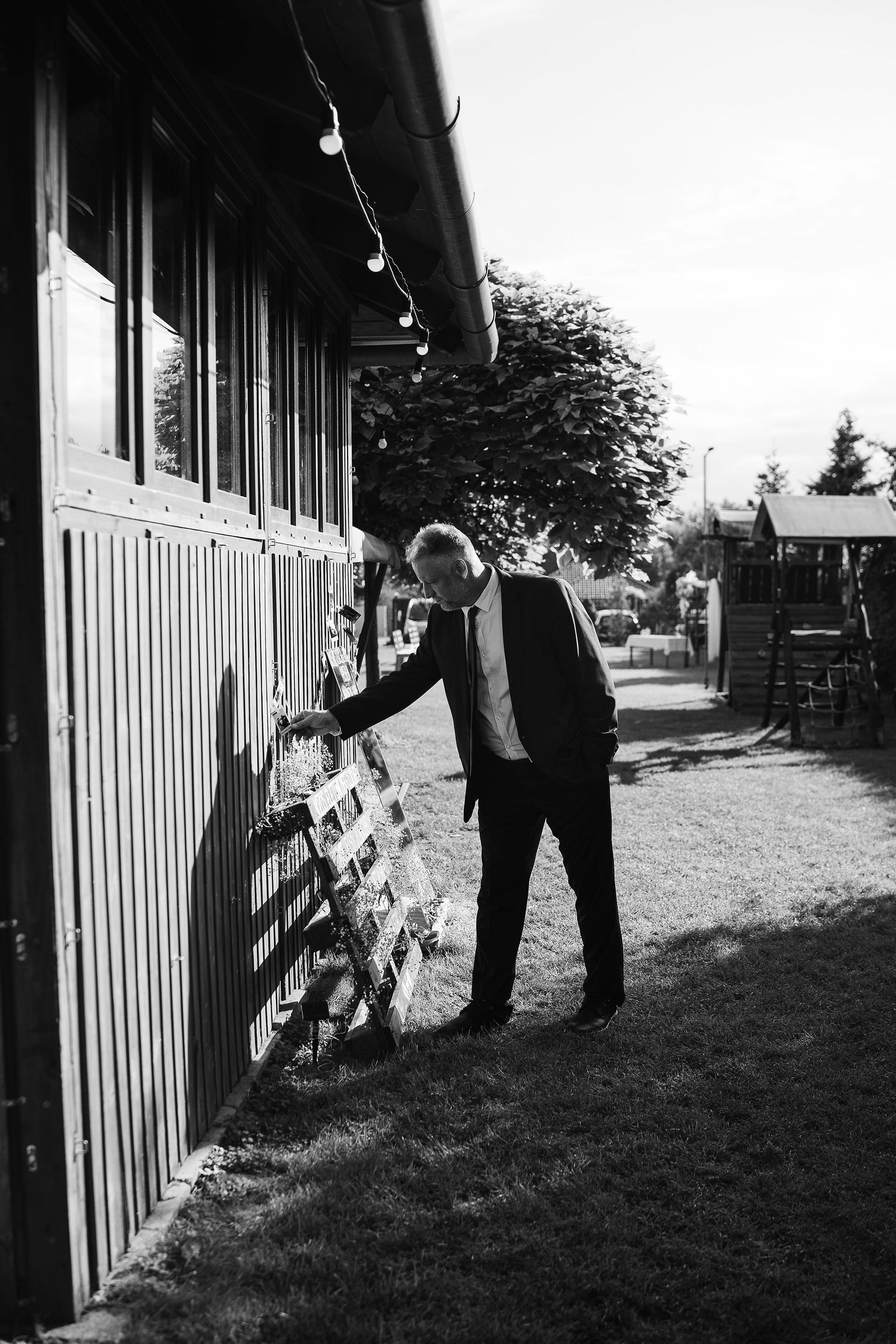 A black and white image of someone examining details on the exterior of a building.
