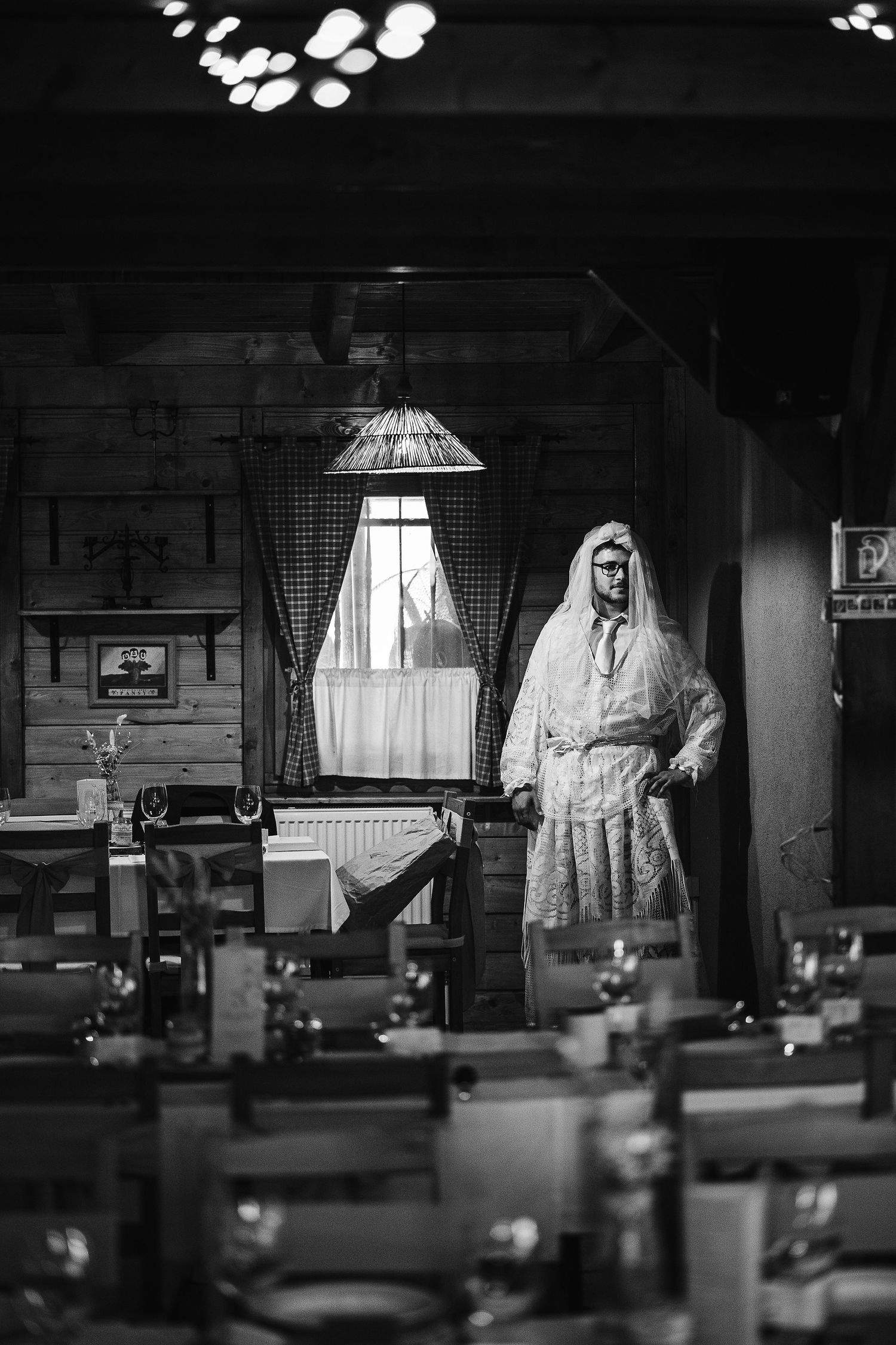 A moody black and white interior shot of a traditional restaurant with wooden tables and chairs.