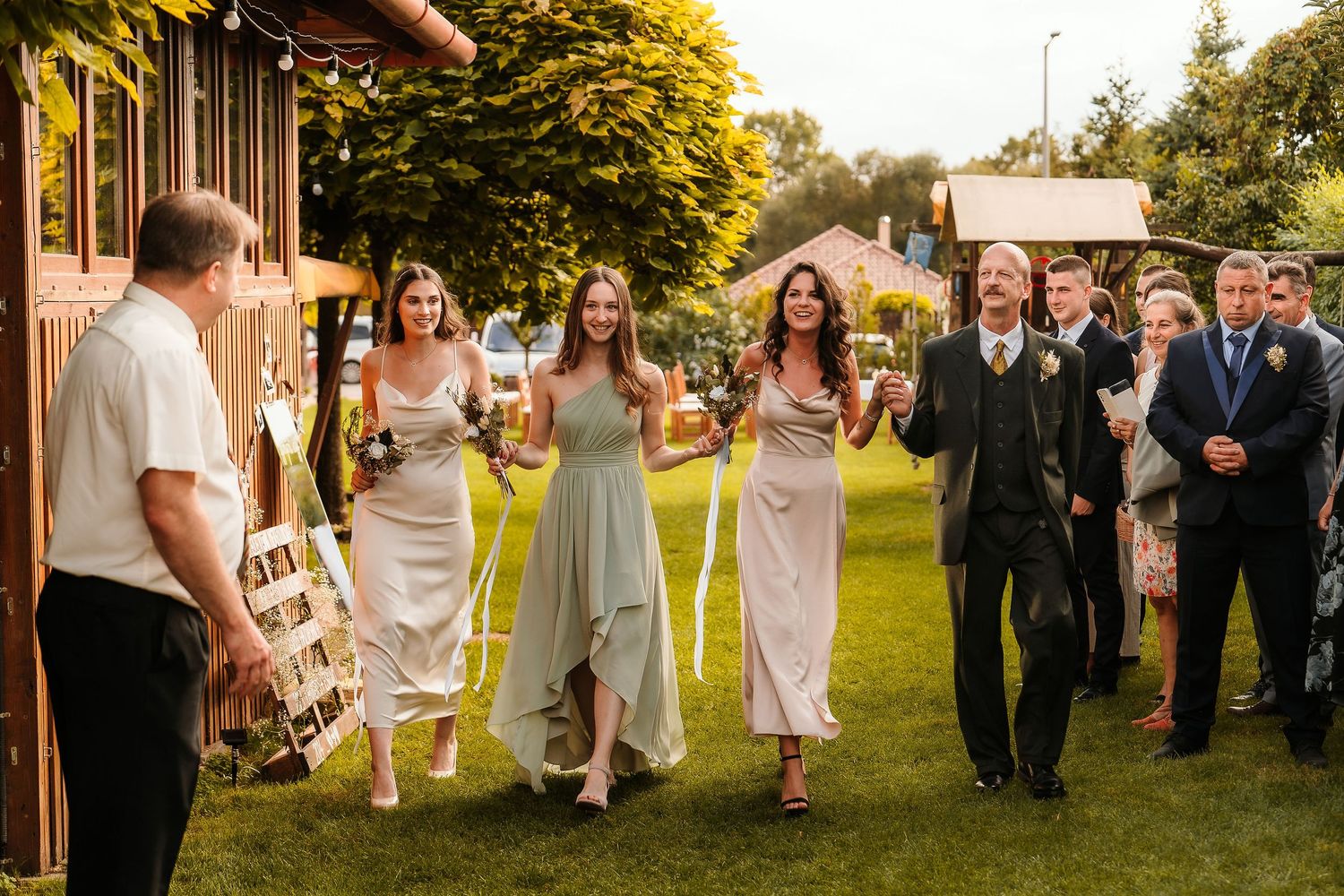 Wedding party walking and laughing together outside a rustic wooden building.