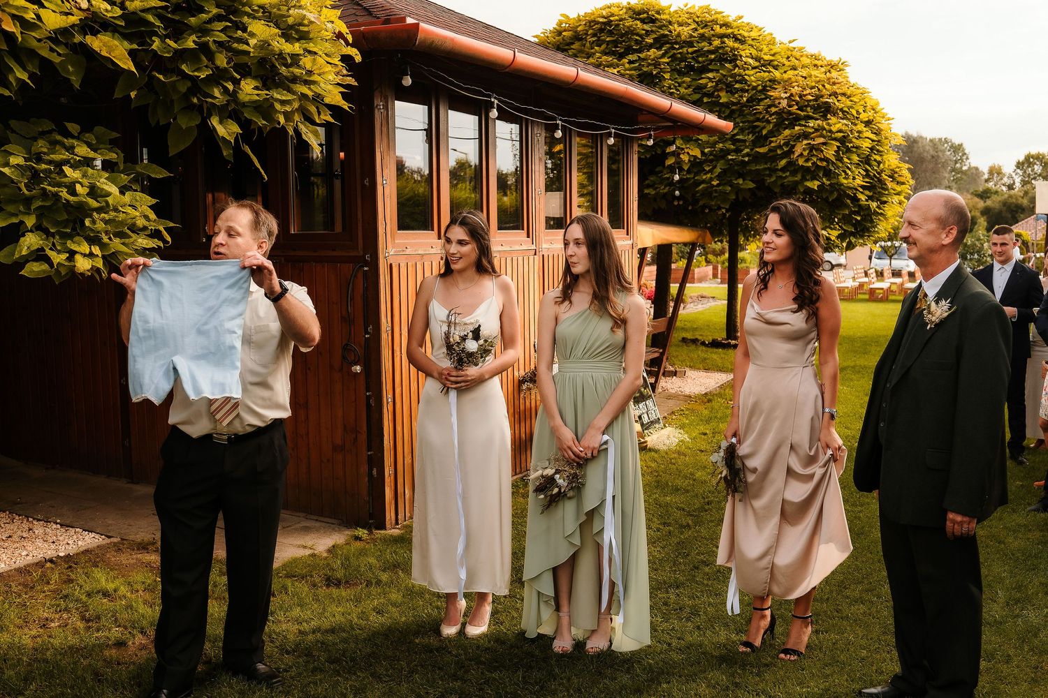 Wedding celebration gathering outside a rustic wooden building with golden hour lighting.