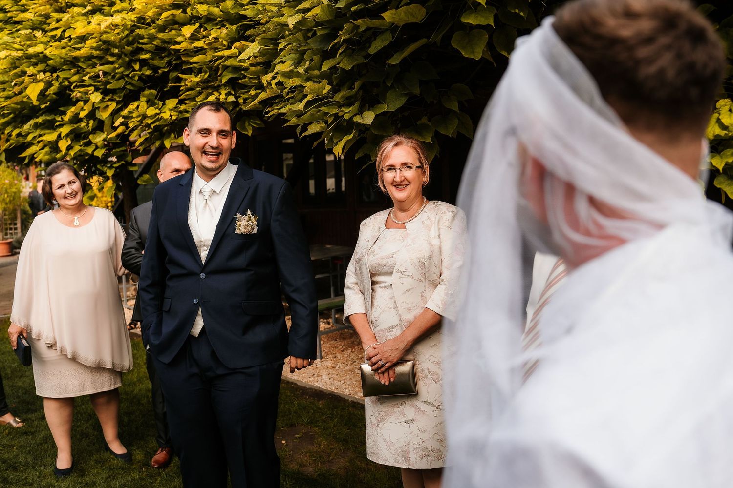 Wedding party members in formal attire gathered outside during golden hour.
