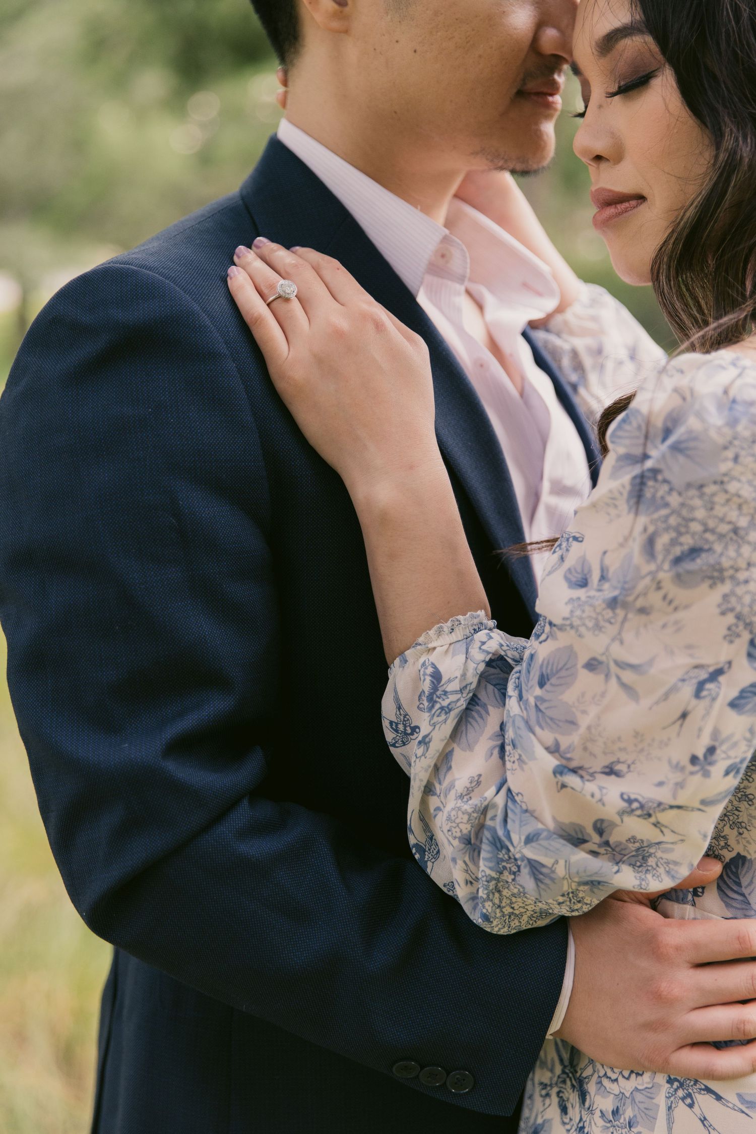Romantic couple in formal attire share an intimate embrace outdoors with delicate lace sleeve details.