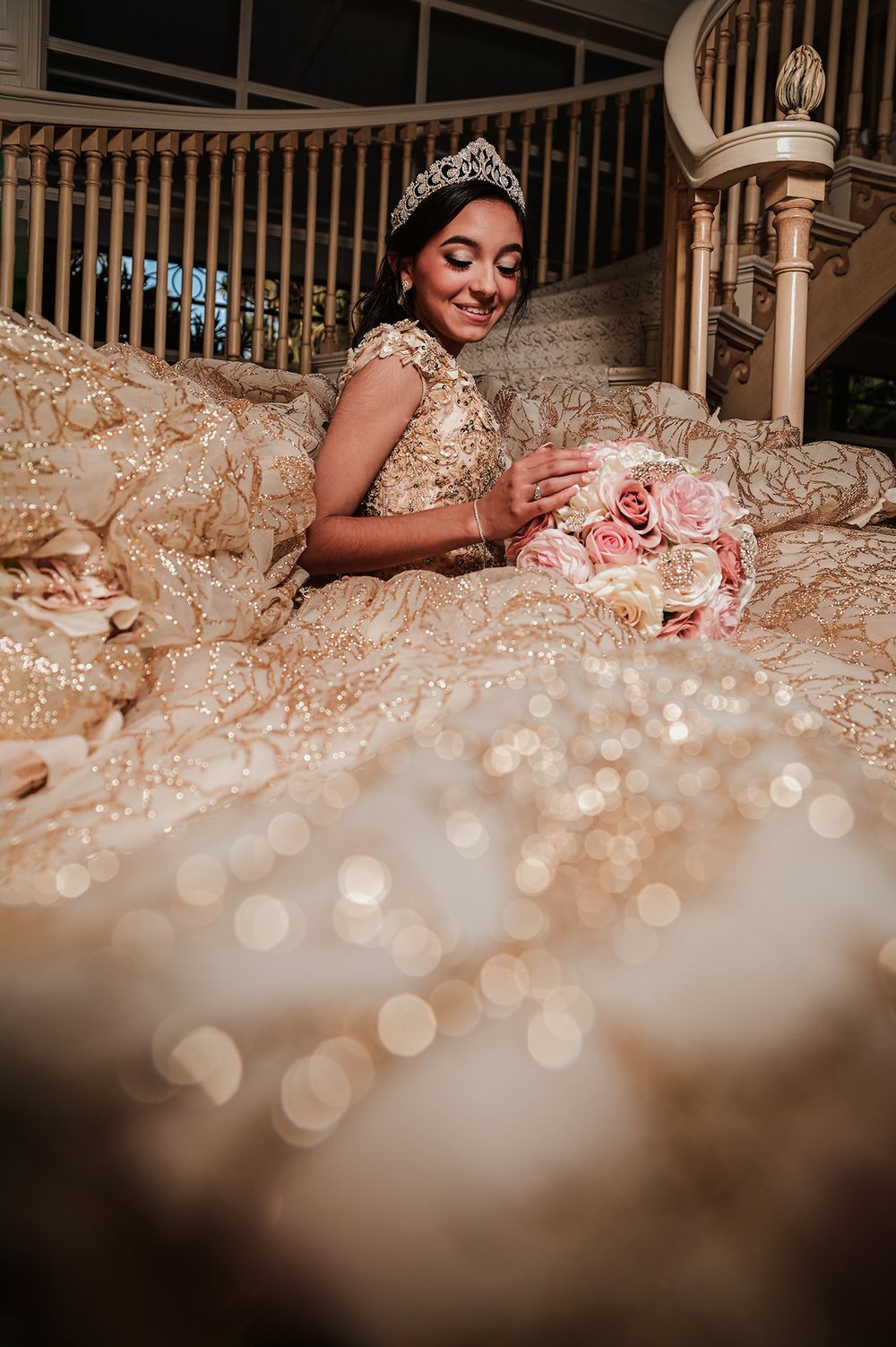 A dreamy photograph of a champagne ballgown with bokeh effects and pink roses.