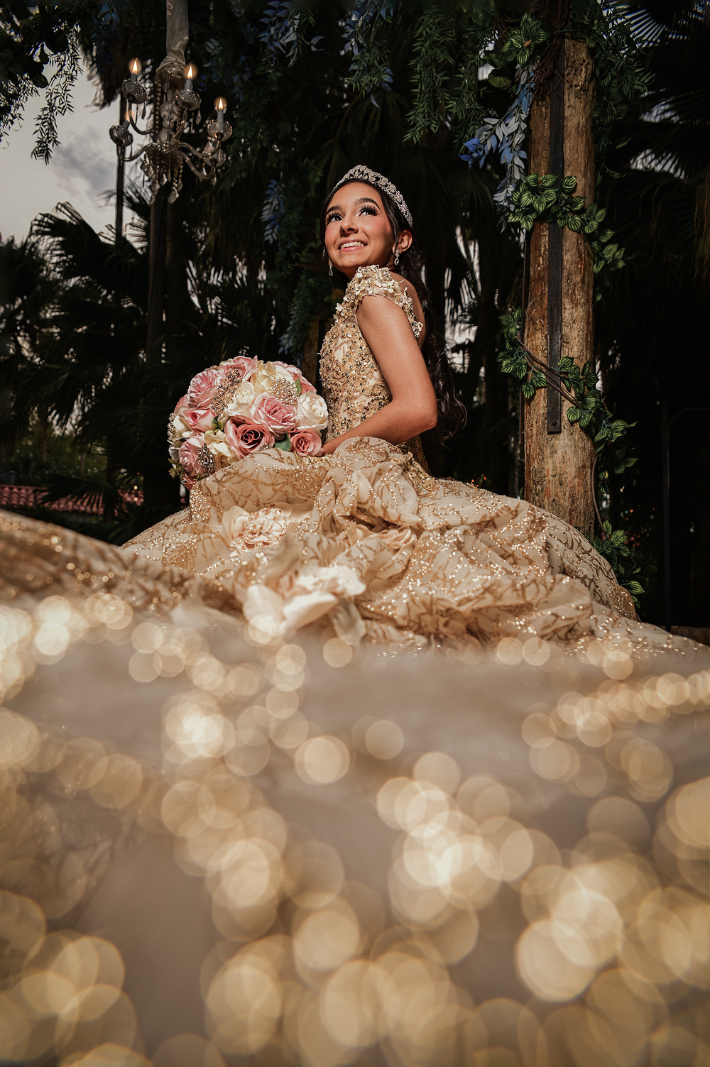 A romantic outdoor portrait with bokeh lighting effects and a champagne-colored quinceañera gown.