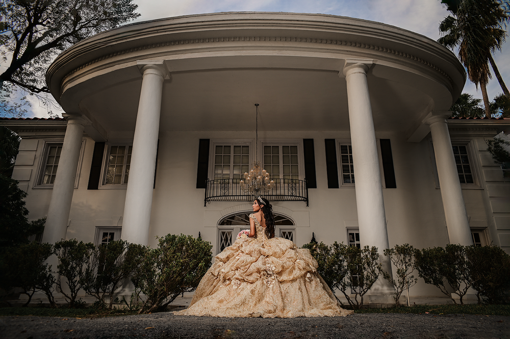 A wide shot of a classical white columned mansion with a ballgown in the foreground.