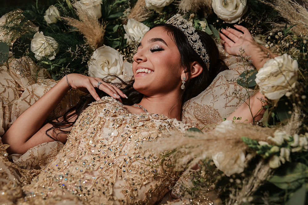 A dreamy quinceañera portrait with white roses and glitter details on a champagne gown.