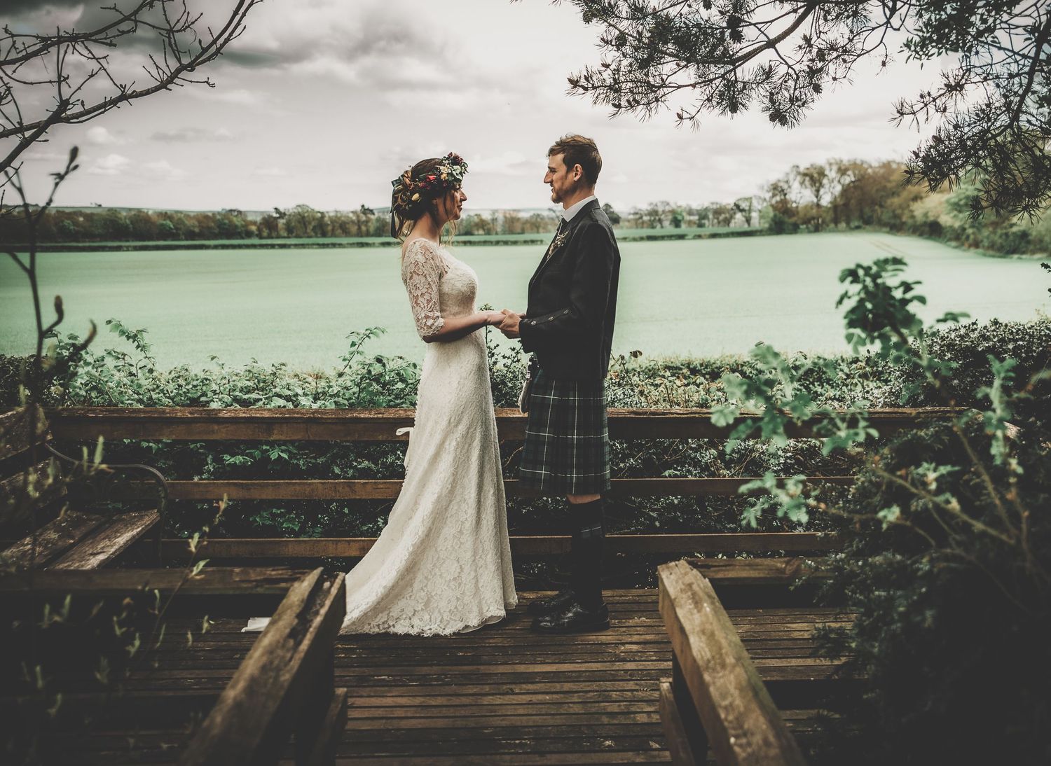 A couple shares an intimate moment on a wooden dock overlooking a serene lake.