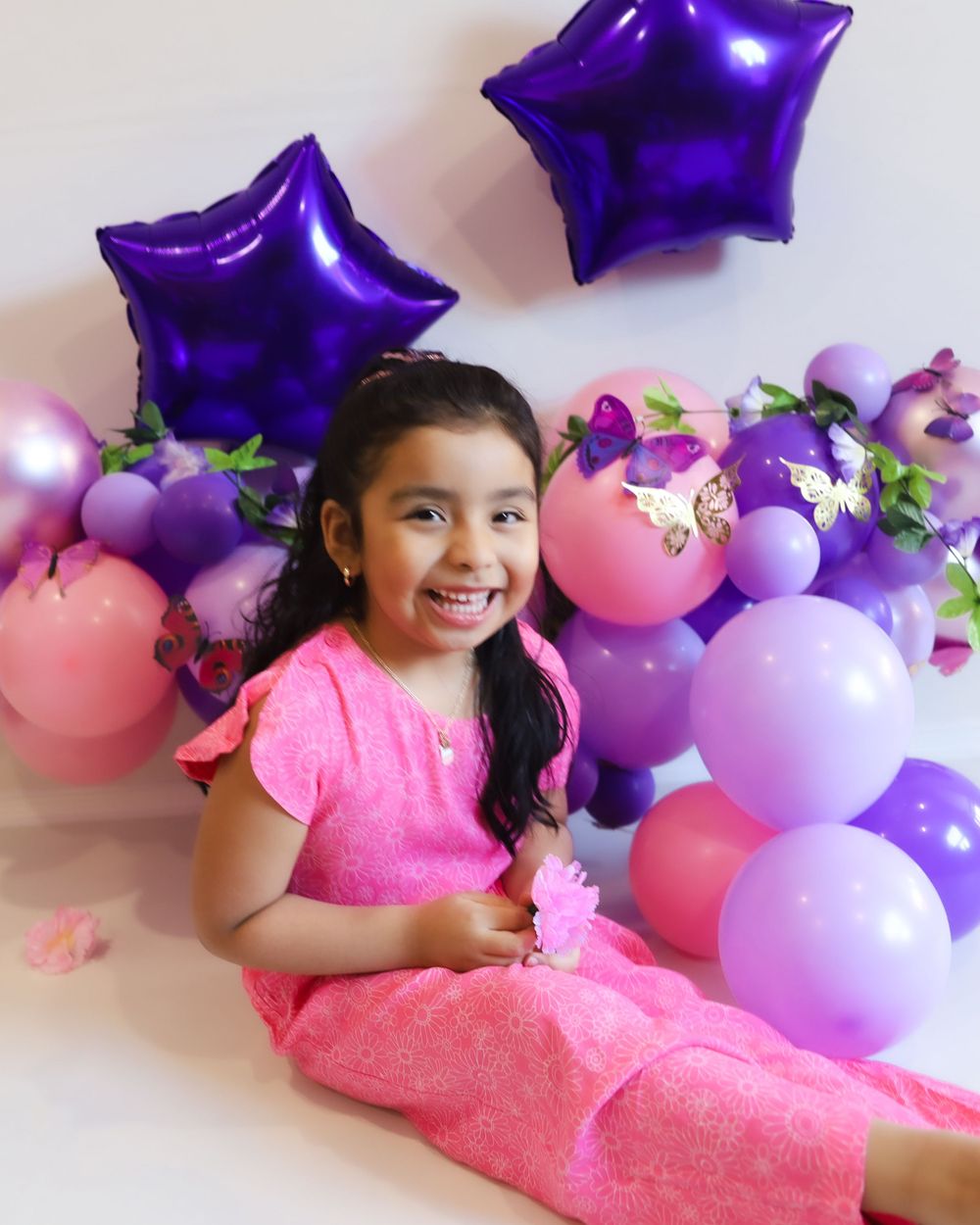Pink and purple balloon backdrop with star decorations for a birthday photoshoot.