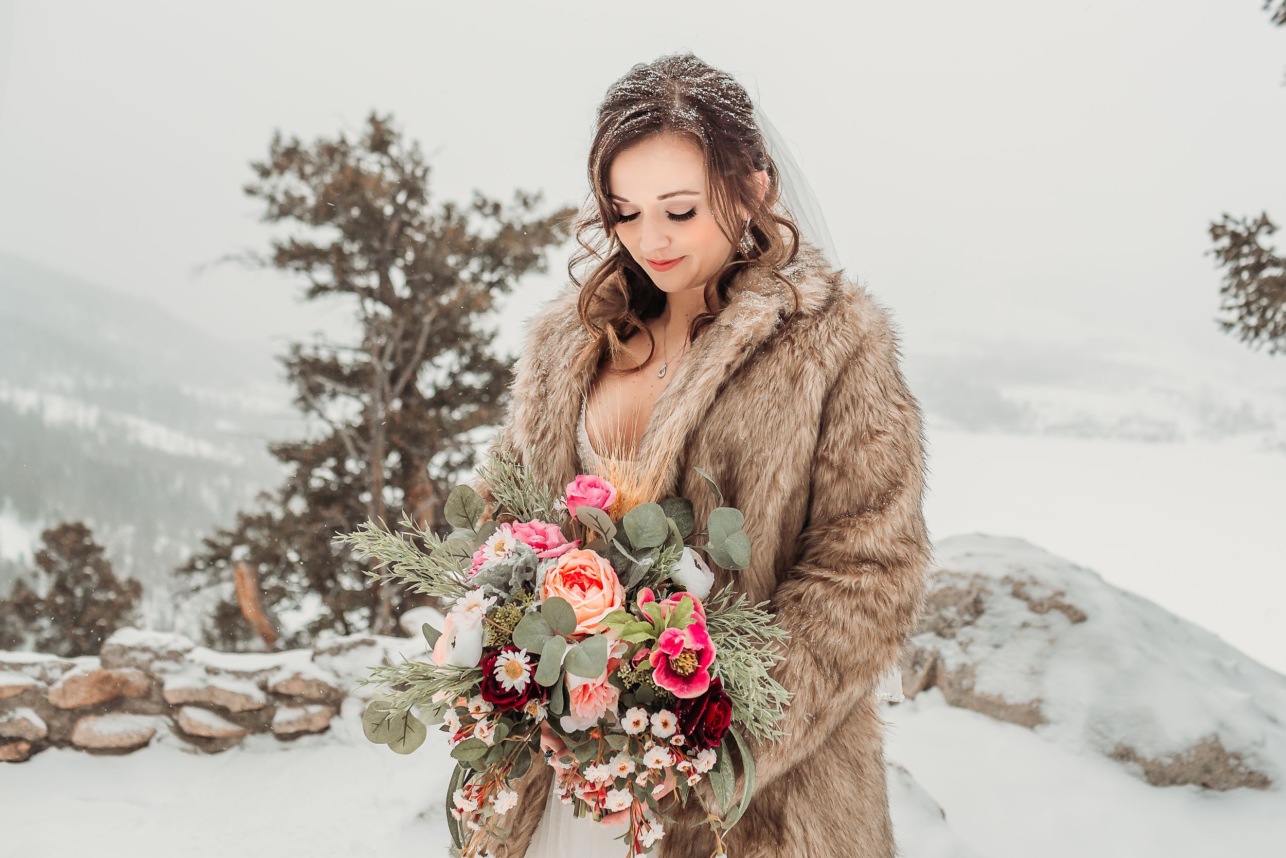 Bride poses in a fur coat with her bouquet in the mountains in Breckenridge, CO.