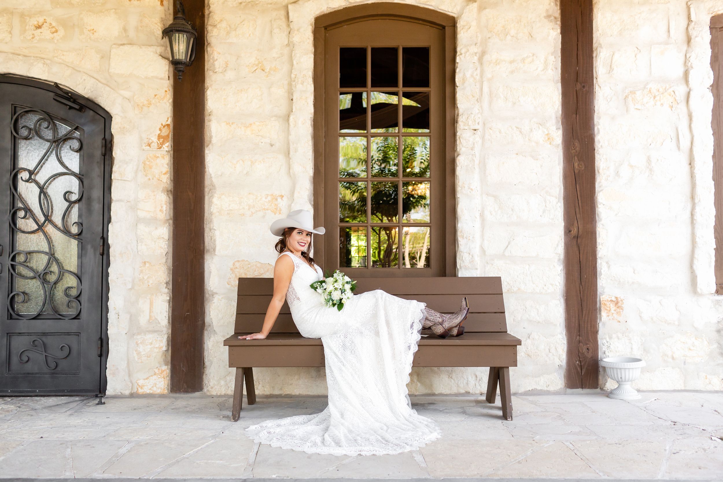 Bride sits in order to show of her cowboy boots and hat at her bridal portrait session in Houston, TX.