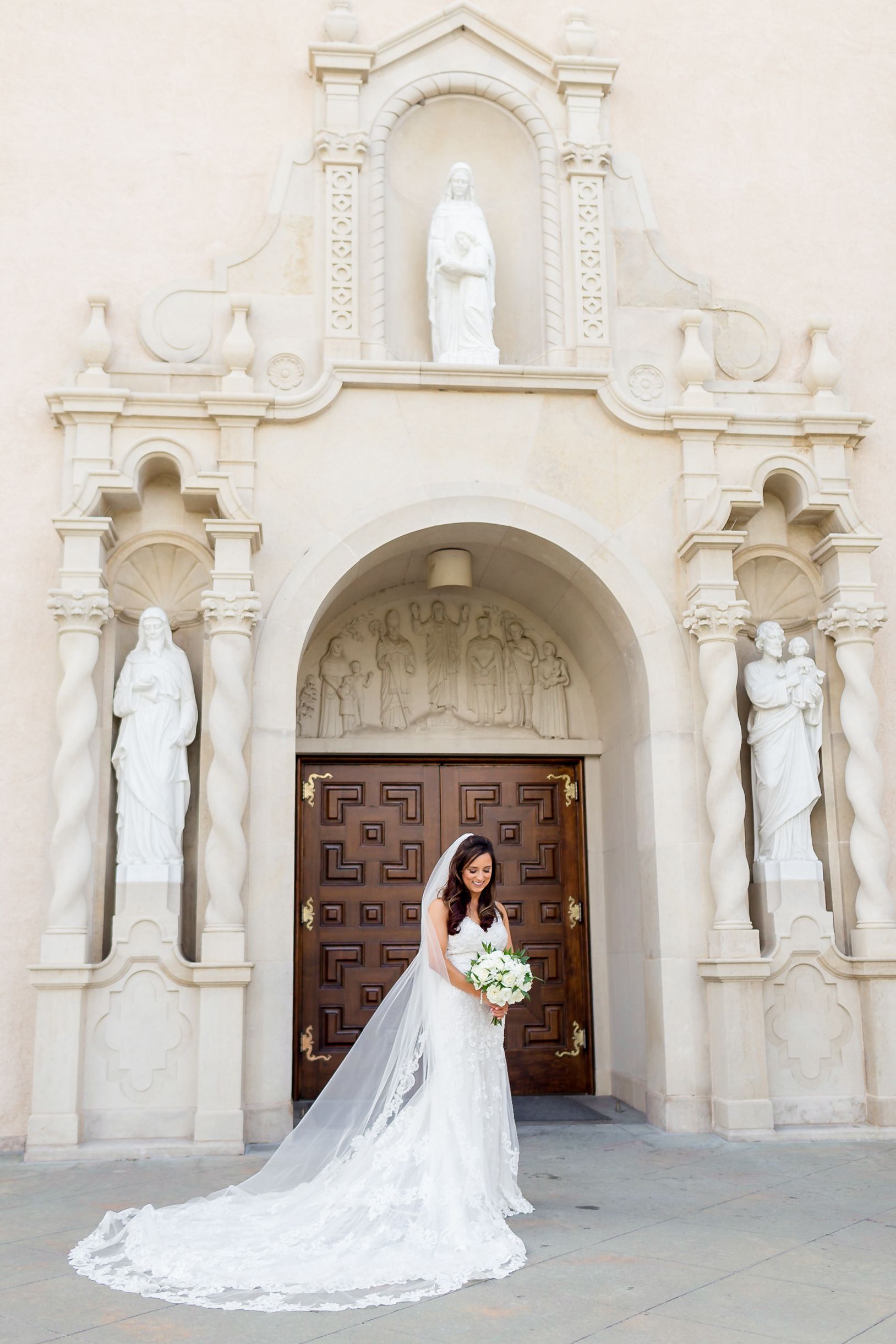 Bride looks down at her bouquet outside of a church in Houston, TX.