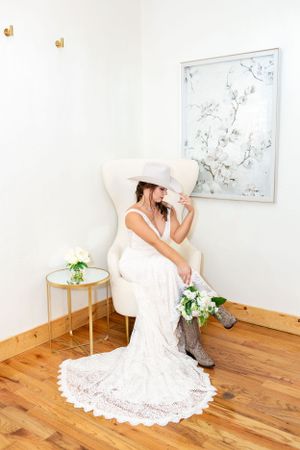 Megan touches the tip of her cowboy hat at her bridal session at the Sprins Event Venue in Houston, TX.