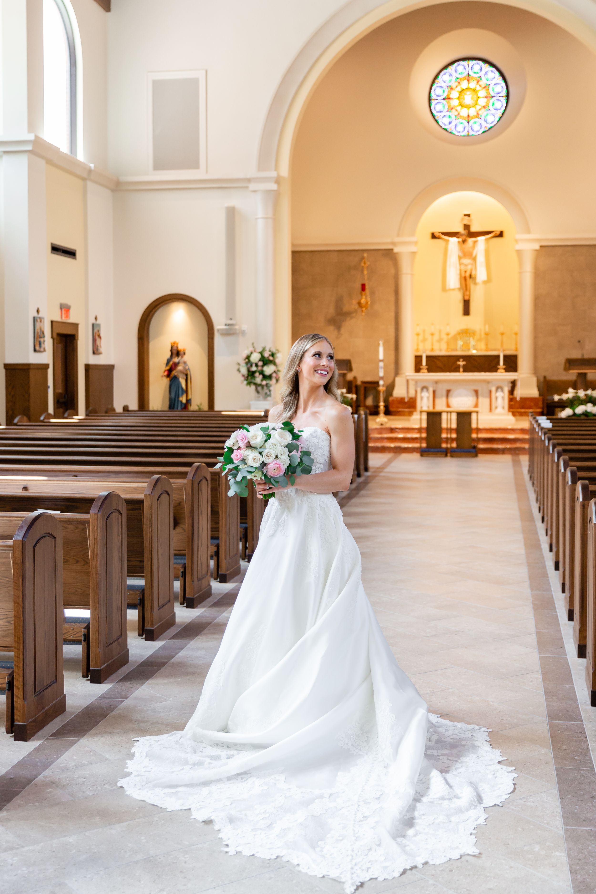 Bride poses with her bouquet in the aisle of a church in Houston, TX.