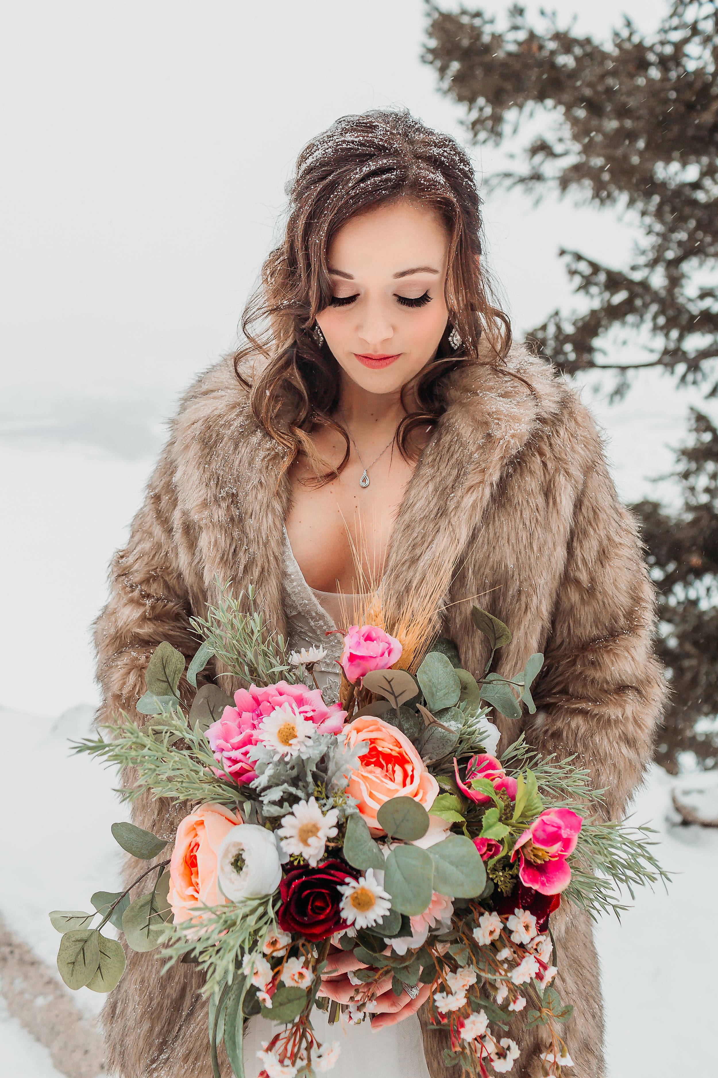 Bride poses in a fur coat with her bouquet in the mountains in Breckenridge, CO.