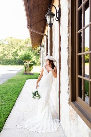 Bride casually leans against the outside wall of the Springs Event Venue for her bridal session.