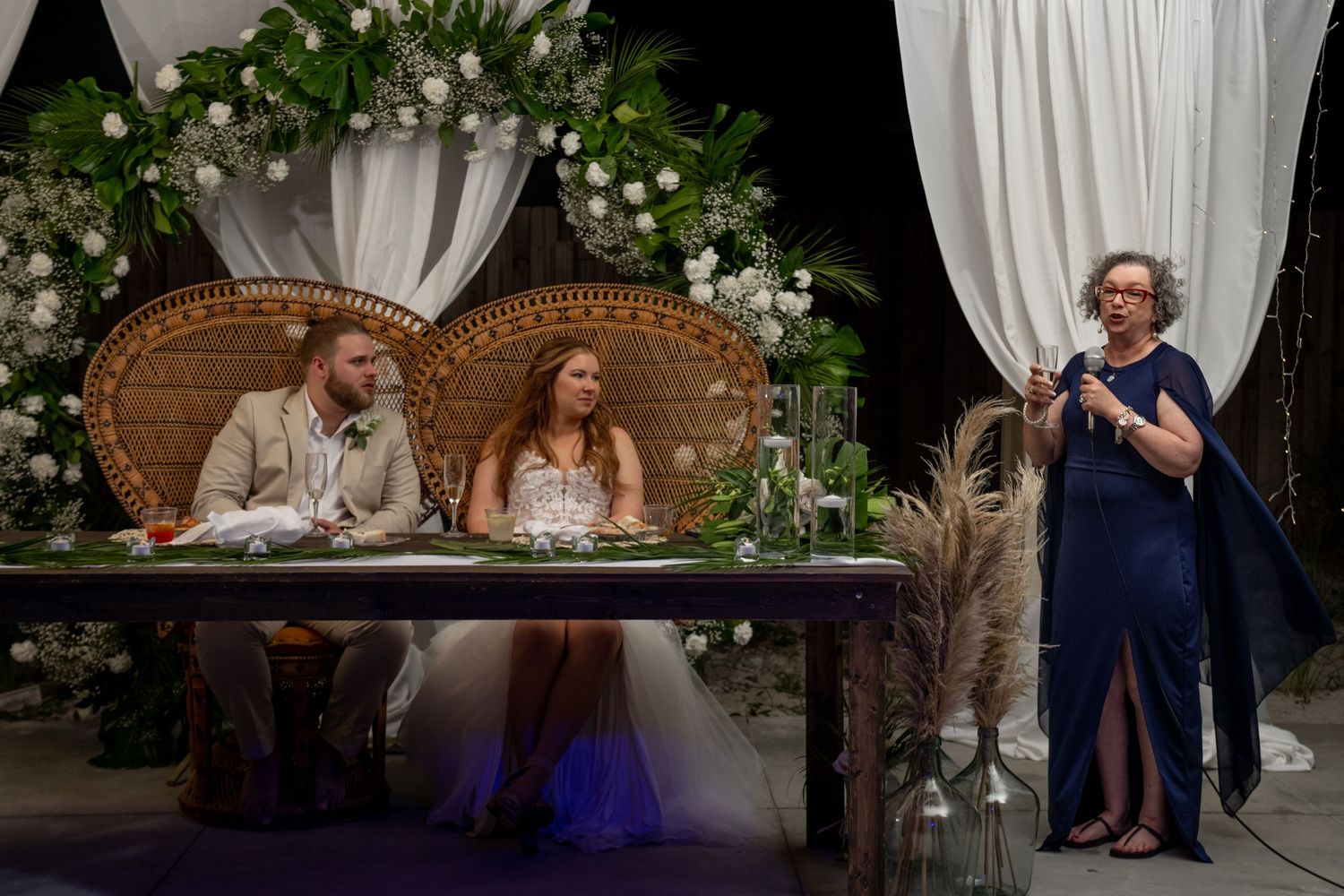 Wedding reception scene with decorative floral arrangements and ornate seating for the couple.