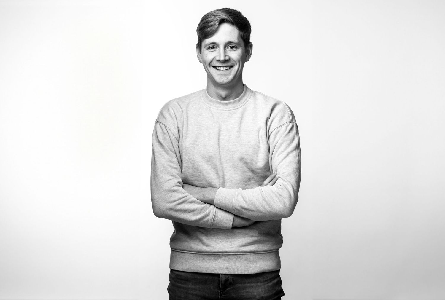 Portrait of Jack Lyons in grey sweater against white background.