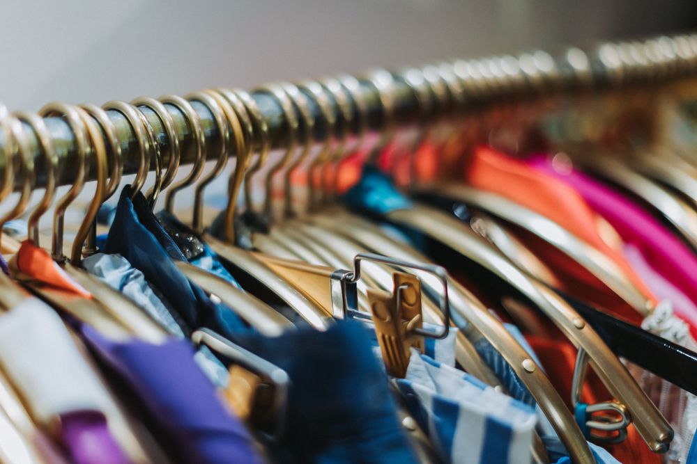 A close-up view of colorful clothing hanging on a rack with metal hangers.
