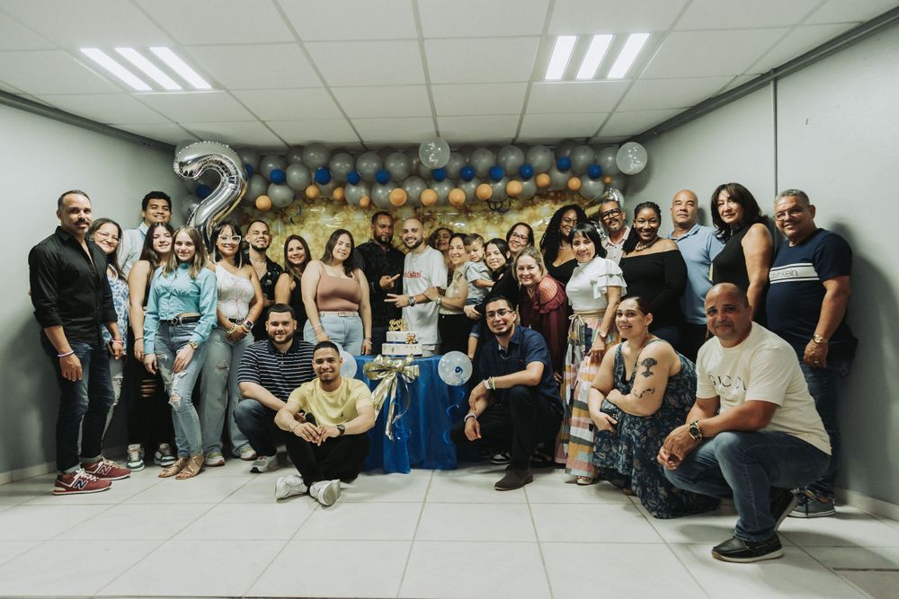 Large group gathered for celebratory photo with balloon decorations and blue accents.
