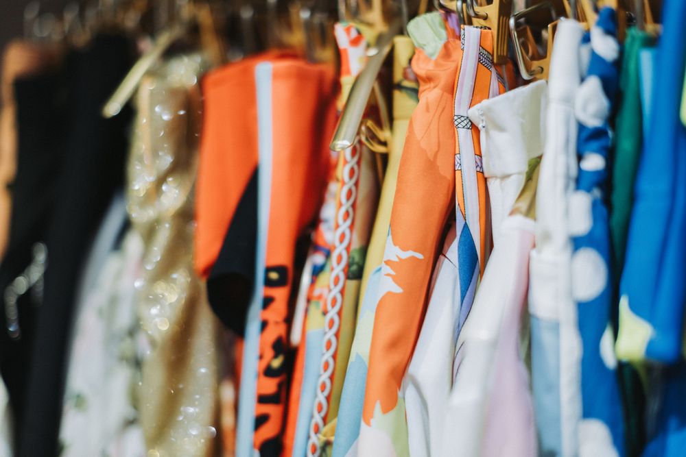 Assorted colorful garments arranged on hangers in a closet.