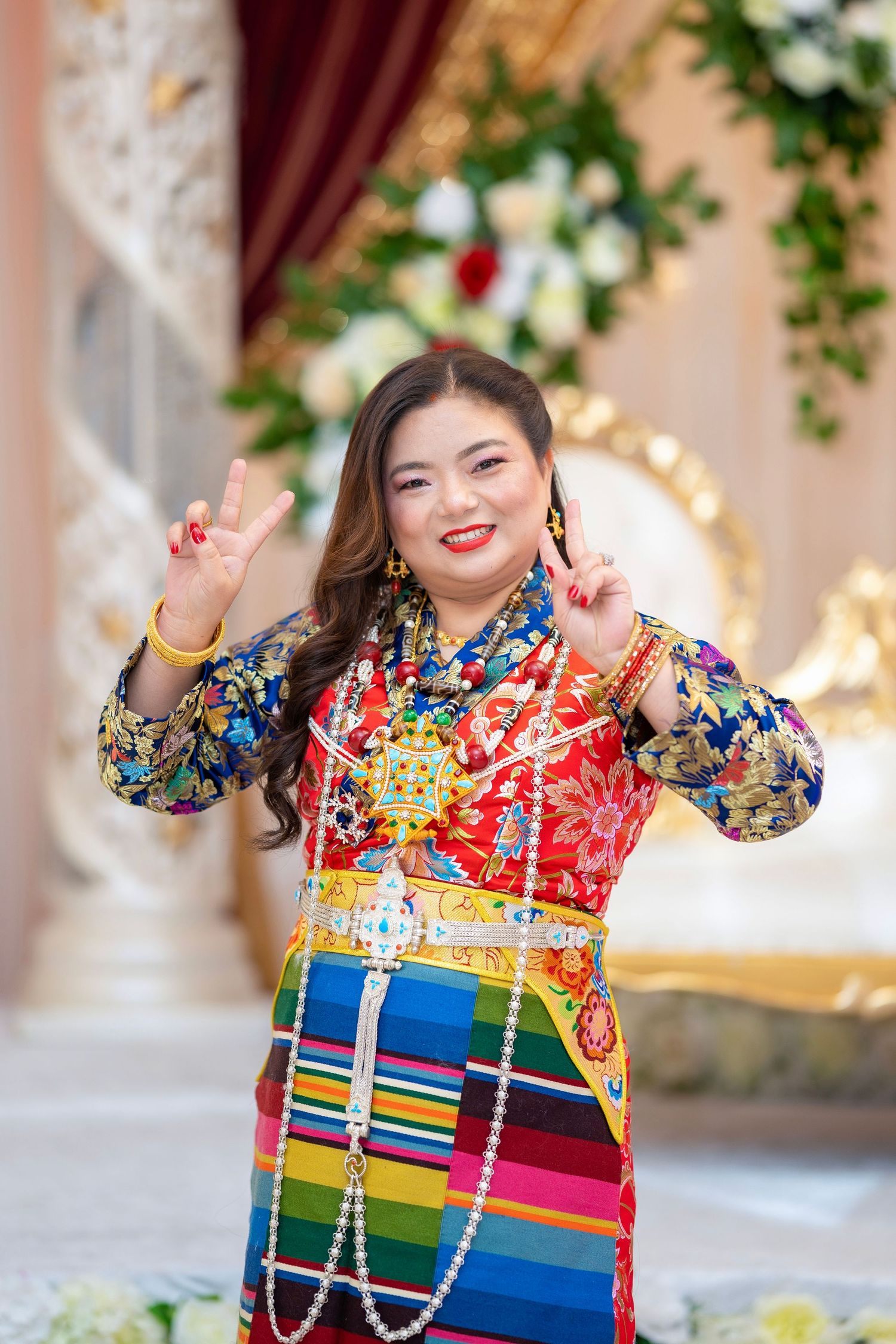 Person in vibrant traditional Nepali dress with colorful striped pattern and jewelry.