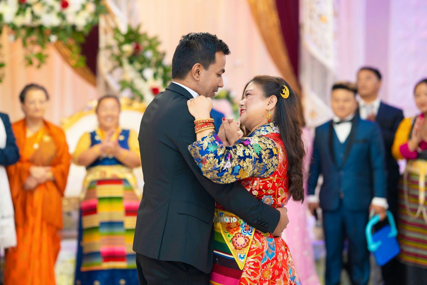 A couple dances joyfully in traditional and formal attire during a celebration.