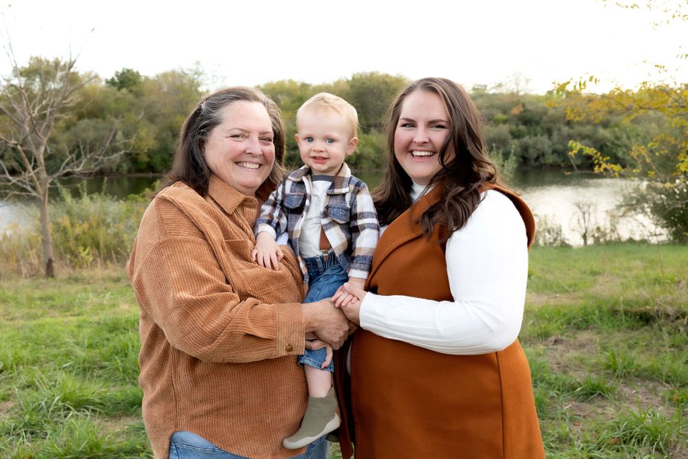 Three people share joyful moment together outdoors in autumn setting.