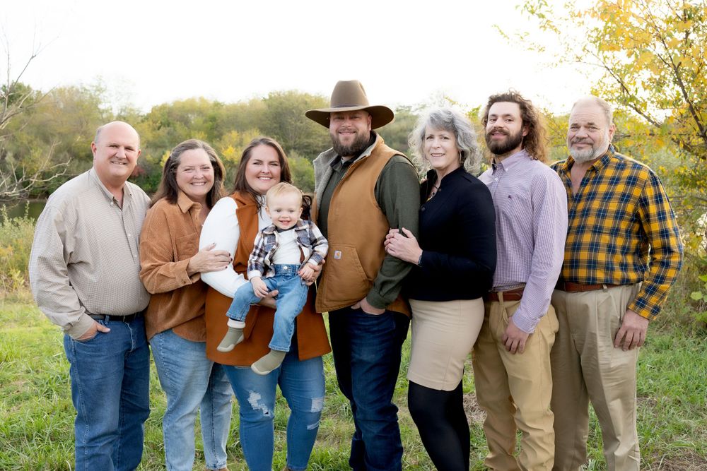 Extended family group poses together outdoors in fall clothing.