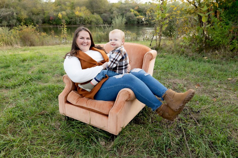 Pair relaxes on vintage brown armchair placed in outdoor natural setting.