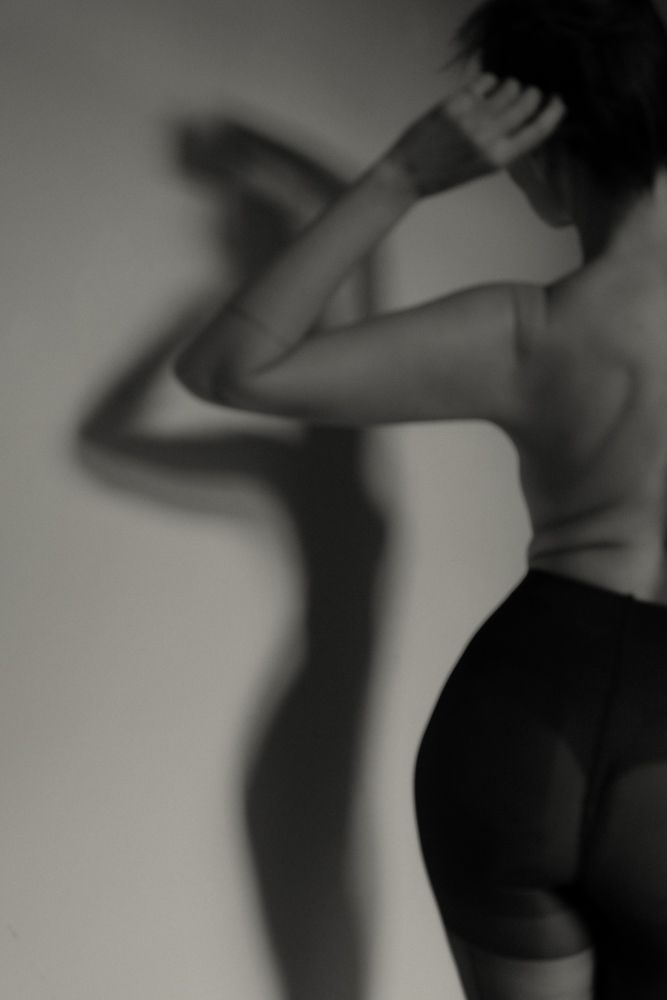 Artistic black and white silhouette photograph showing a figure in athletic wear casting dramatic shadows.
