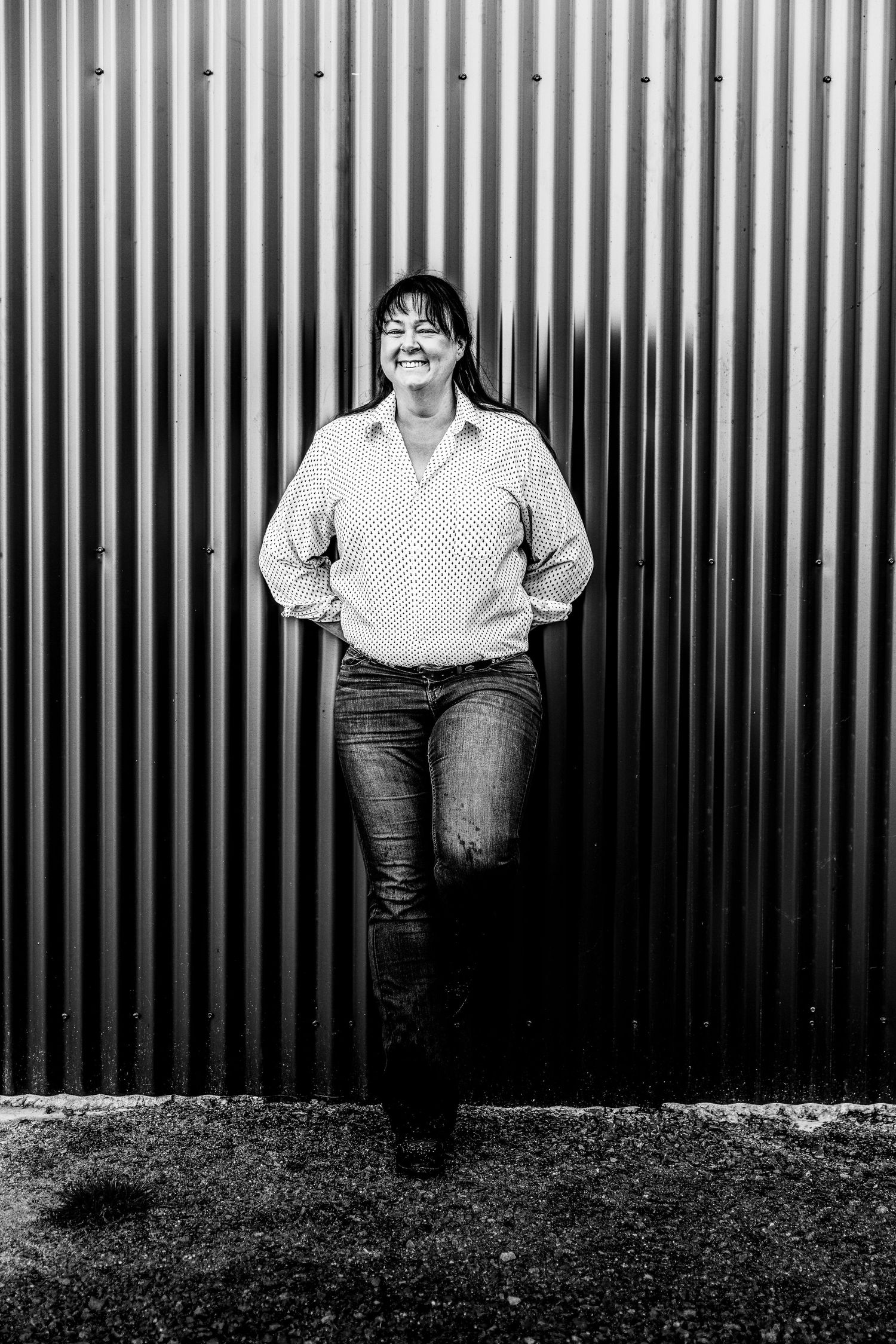 Black and white portrait against corrugated metal wall showing casual style.