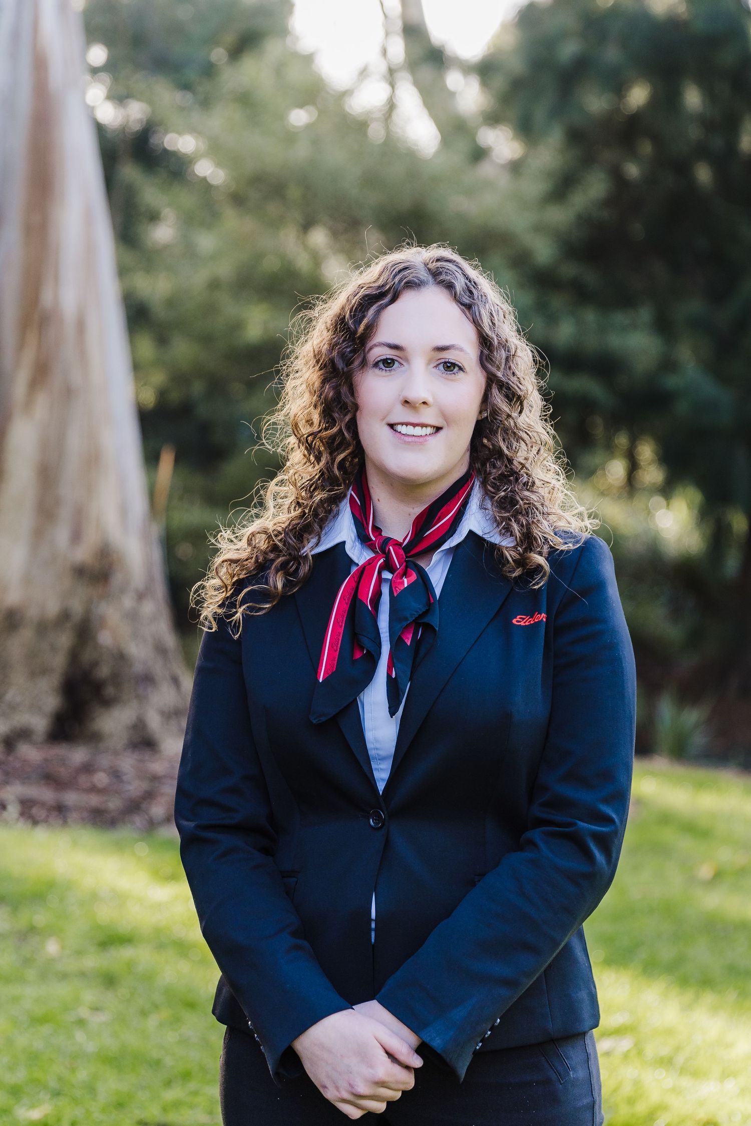 Professional wearing navy uniform with red scarf standing in outdoor setting.