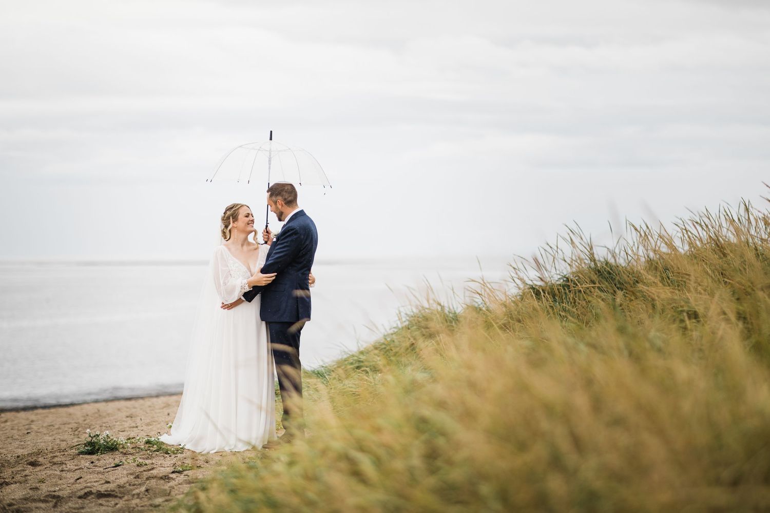A couple poses for wedding photos on a scenic coastal cliff with ocean views.