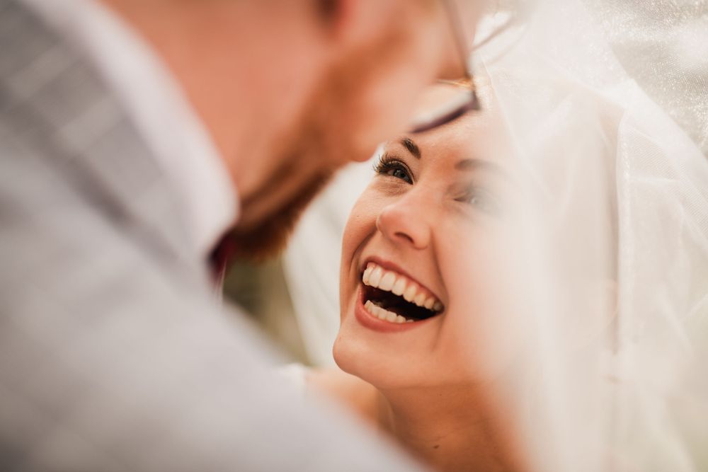 Close up of bride laughing under veil at wedding