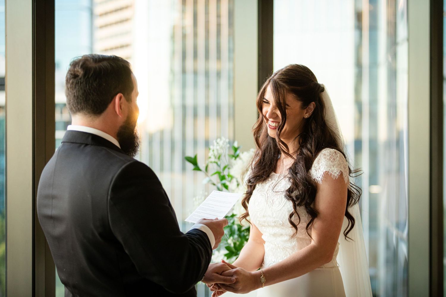 Intimate wedding ceremony moment in modern high-rise with city views.