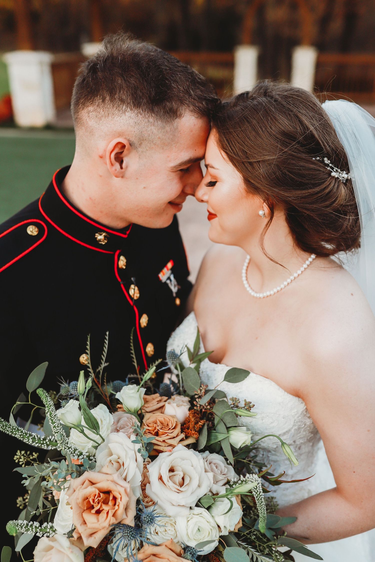 A romantic military wedding photo features a bridal bouquet with peach and white roses against formal attire.