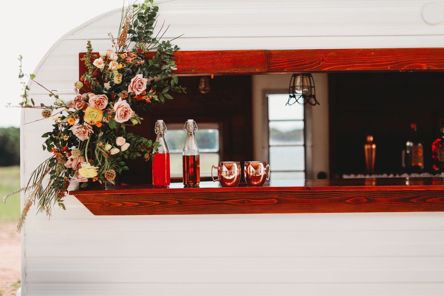 Rustic bar window display decorated with pink florals and cocktail glasses.