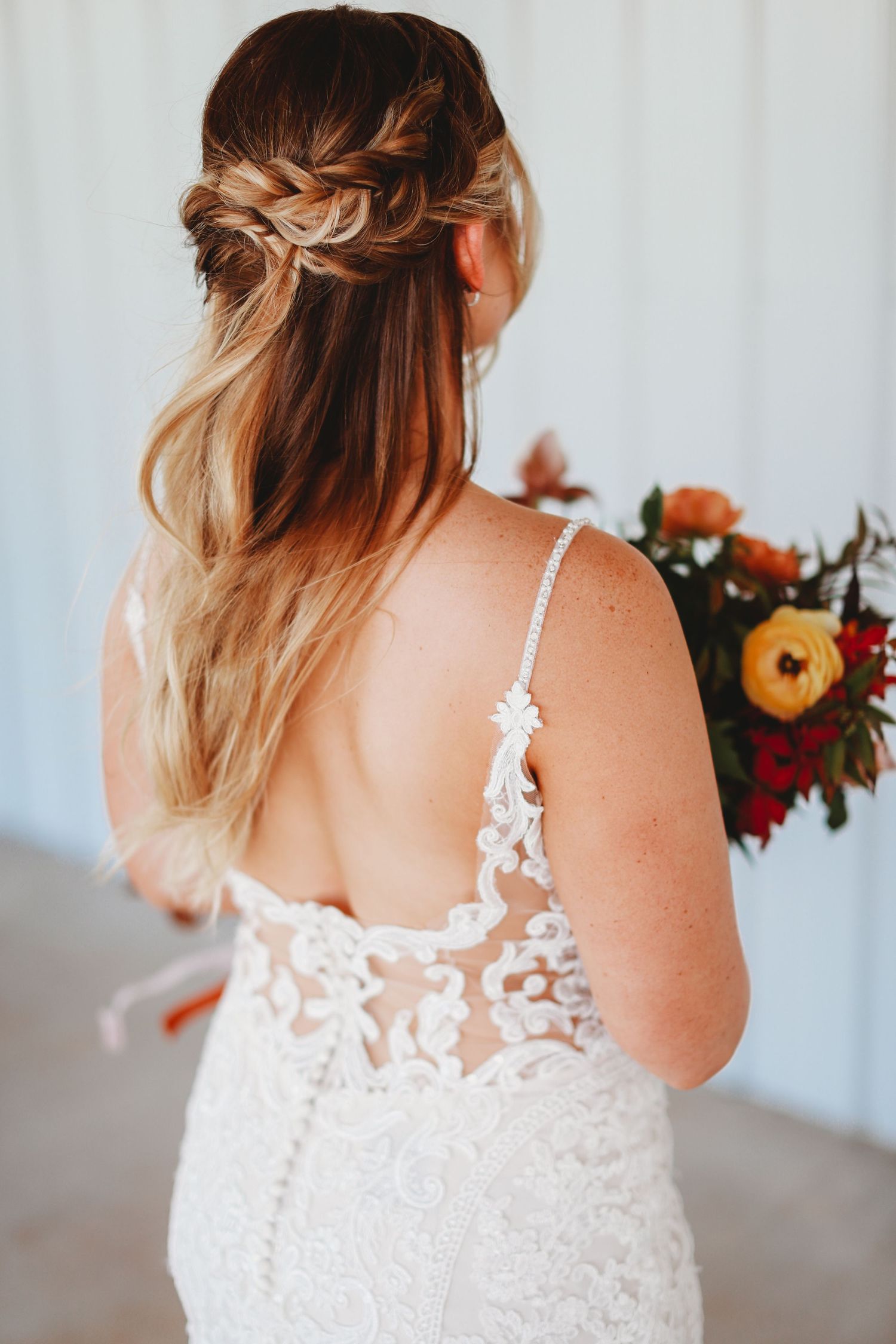 Detailed back of lace wedding dress with intricate braided hairstyle.