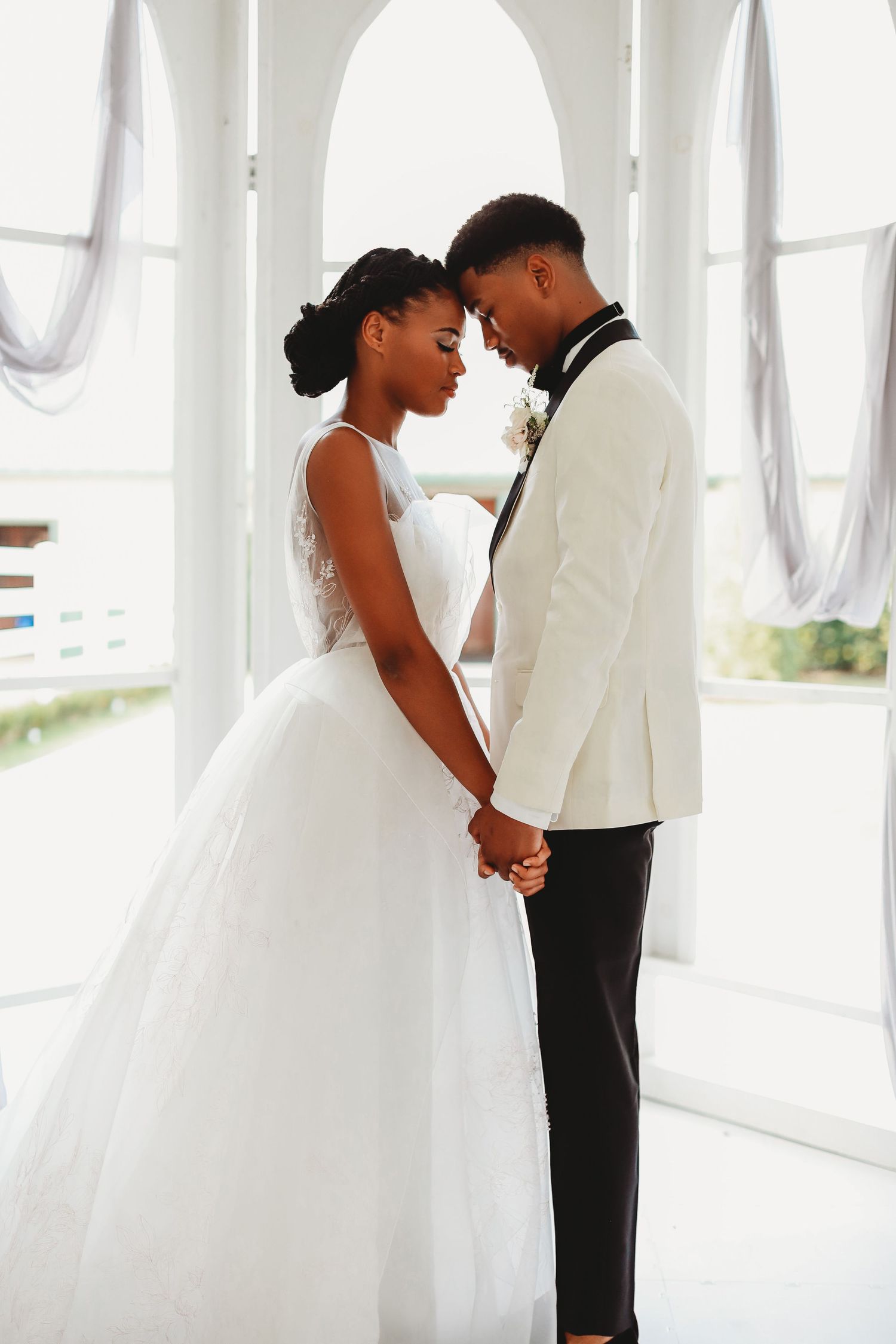 Intimate wedding moment captured in a bright white chapel with elegant arched architecture.