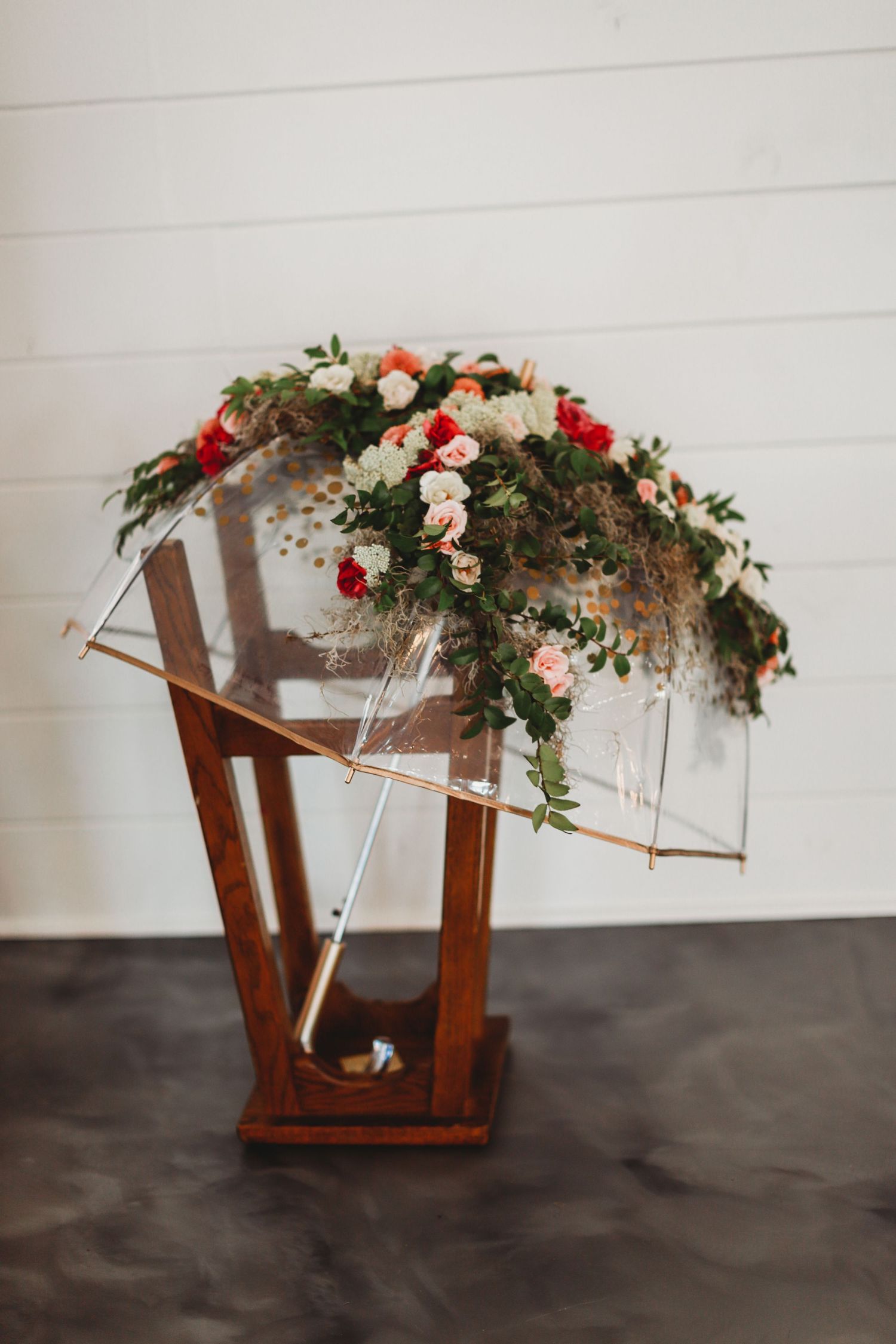 Wooden lantern decorated with pink and red flowers and greenery for wedding decor.